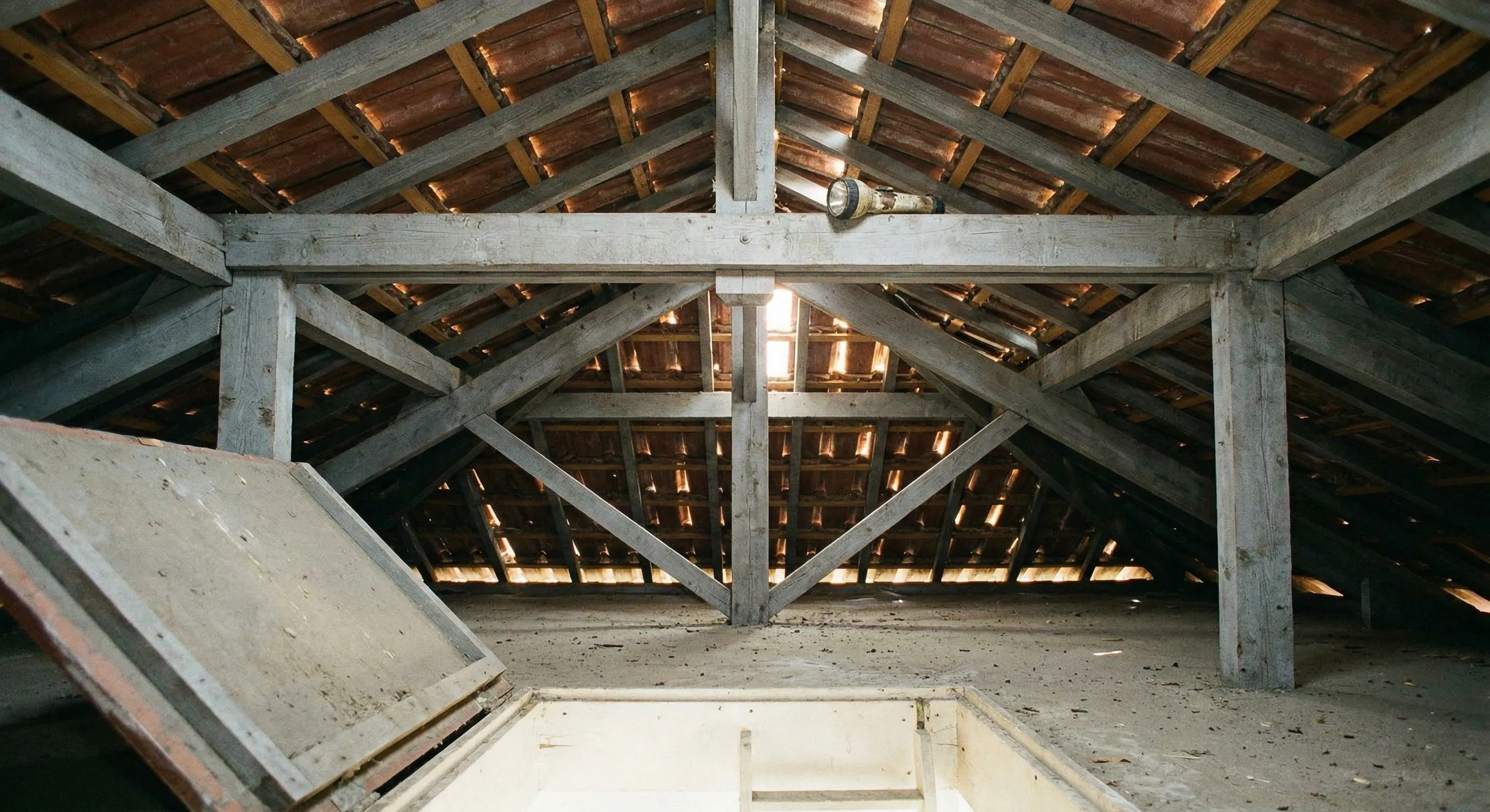 Combles non isolés d'un pavillon girondin avec charpente en fermettes apparentes et tuiles visibles
