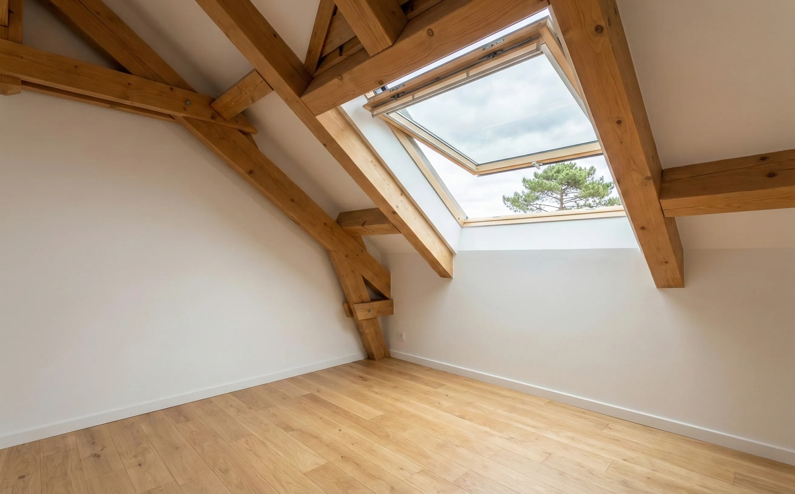 Intérieur de combles éclairés par un velux ouvert à Pessac, charpente bois visible