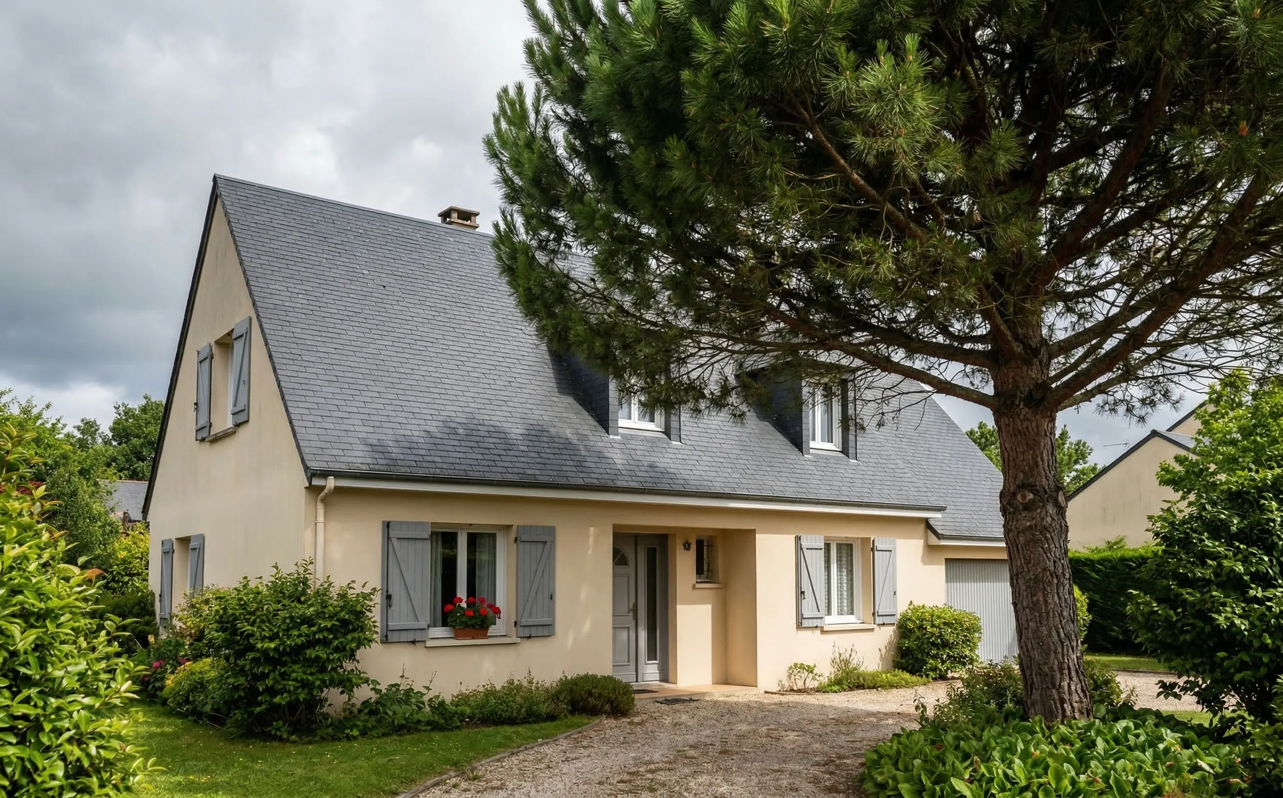 Pavillon girondin avec toiture en ardoise, pins maritimes en arrière-plan et ciel couvert atlantique