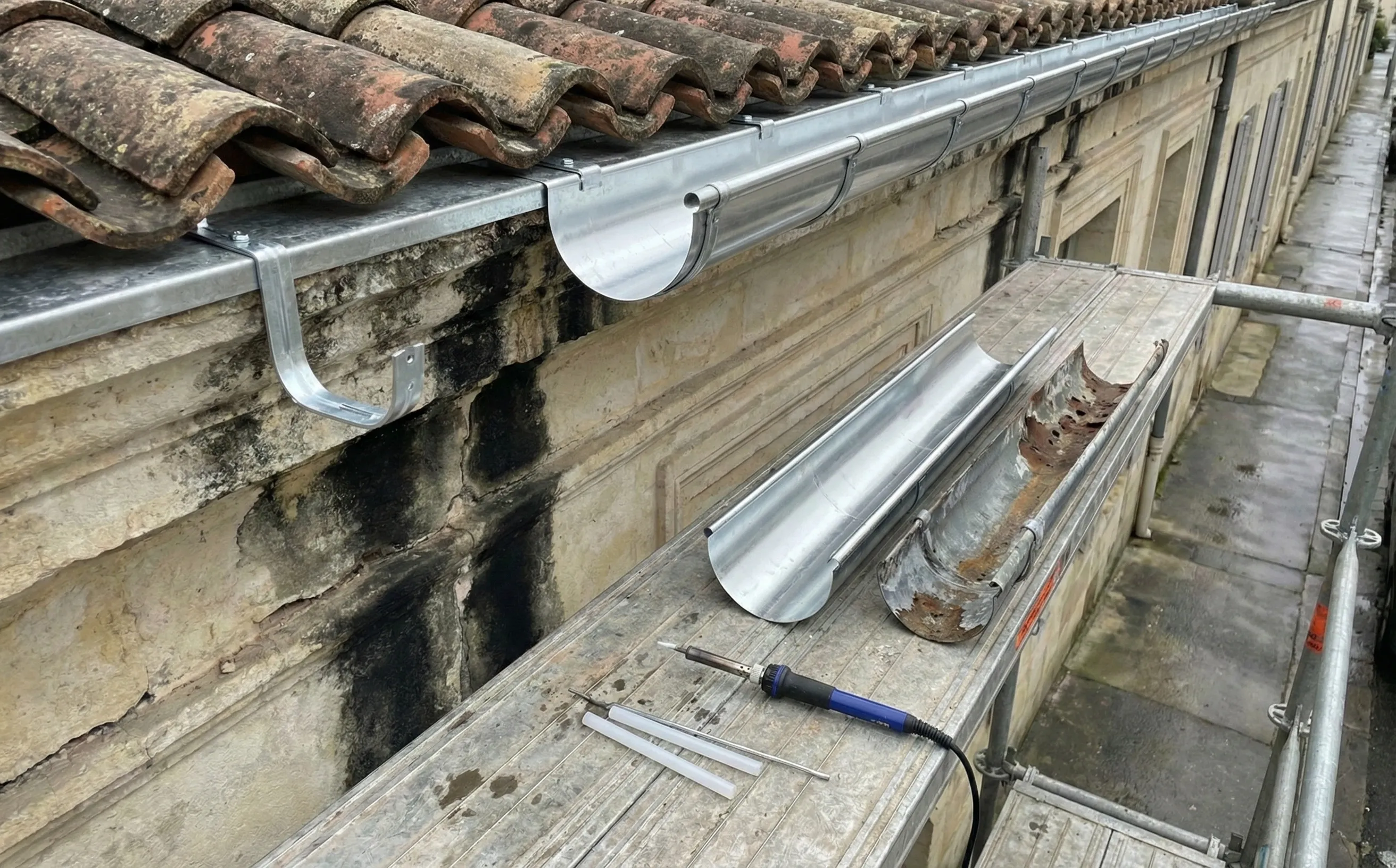 Pose de gouttière demi-ronde en zinc neuf sur génoise d'une maison en pierre à Pessac-Centre