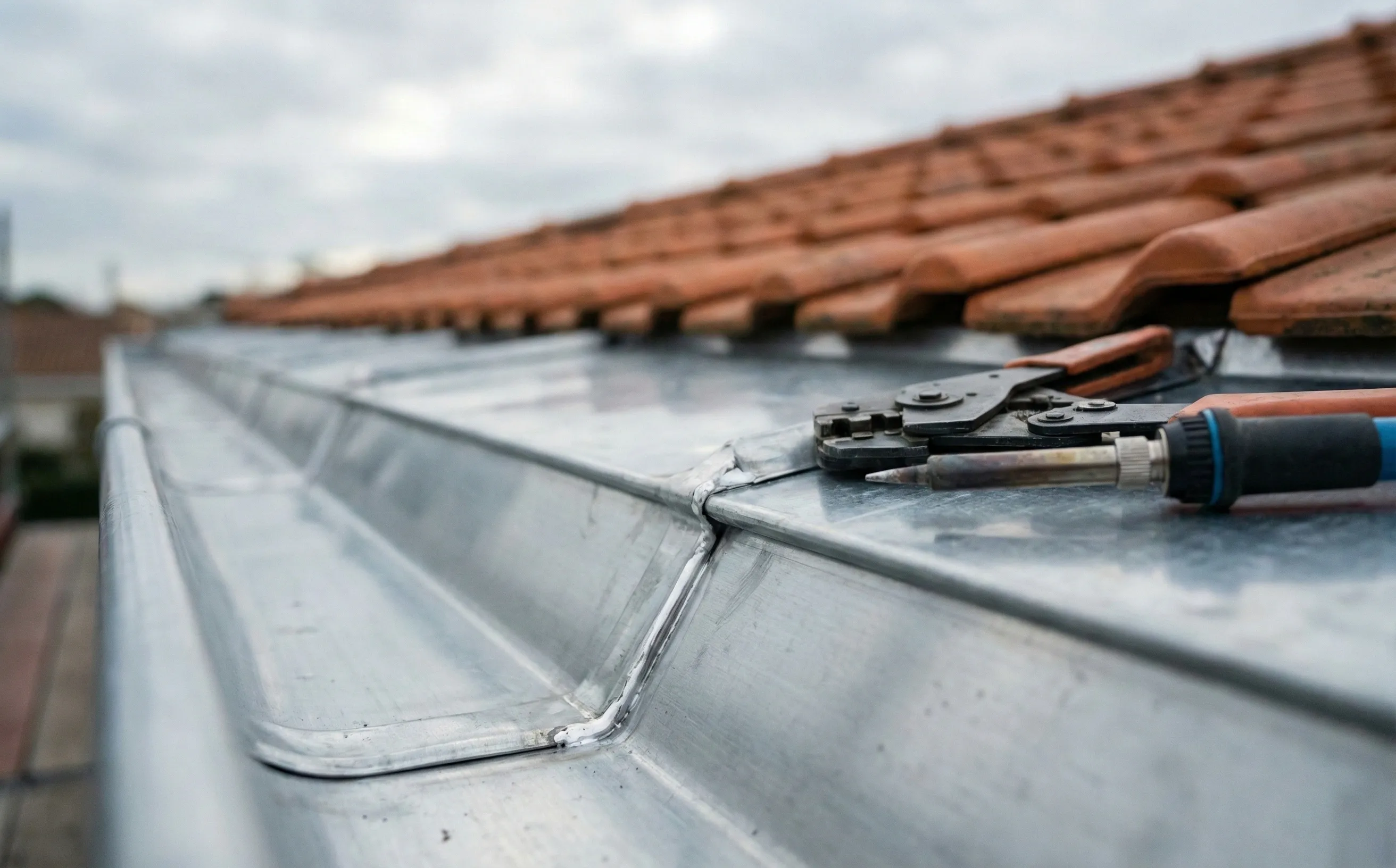Soudure zinc sur un raccord de chéneau, détail du travail de zinguerie à Pessac