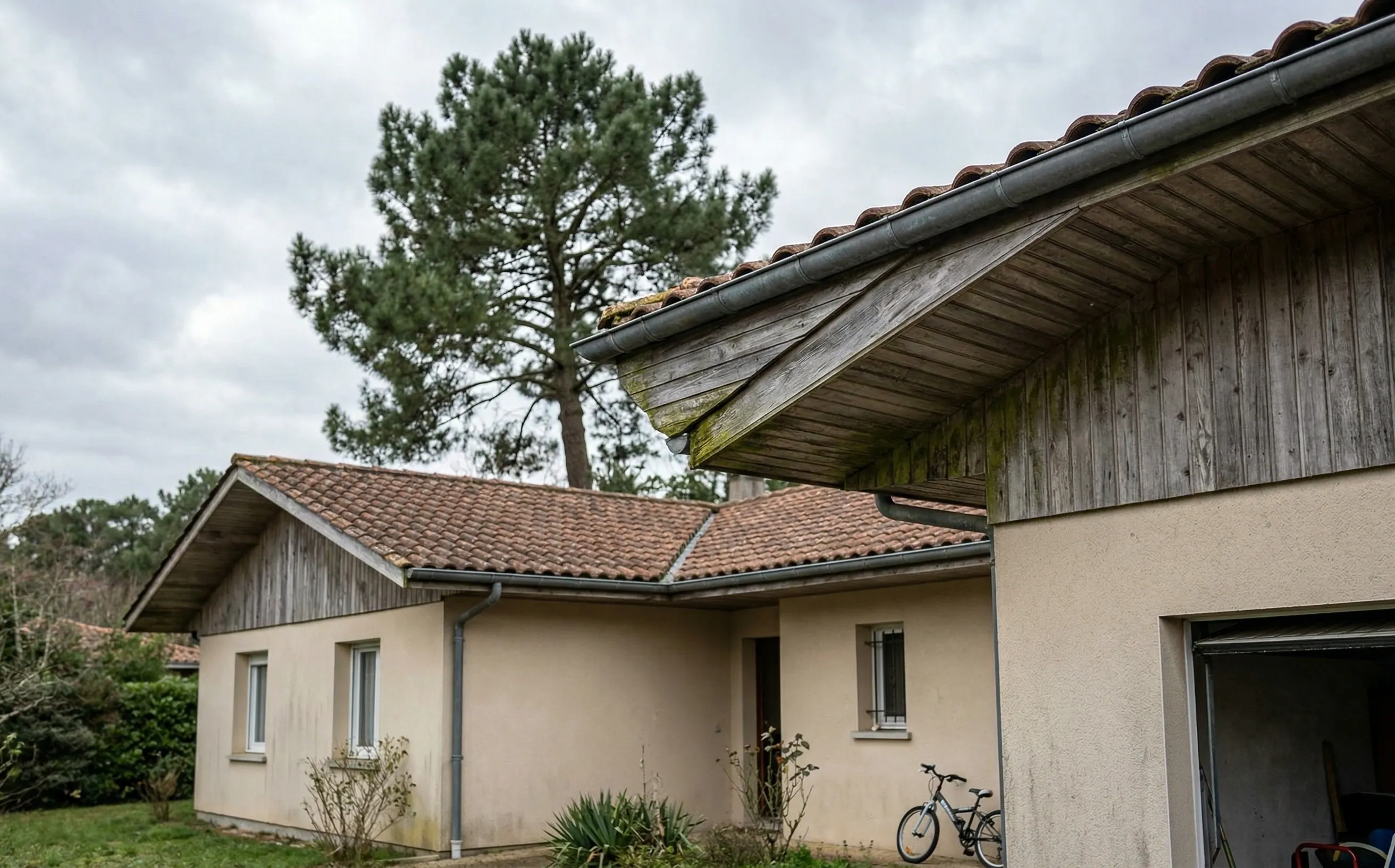 Sous-face en bois grisé sous le débord de toit d'un pavillon girondin avec gouttière en zinc patiné et pin maritime
